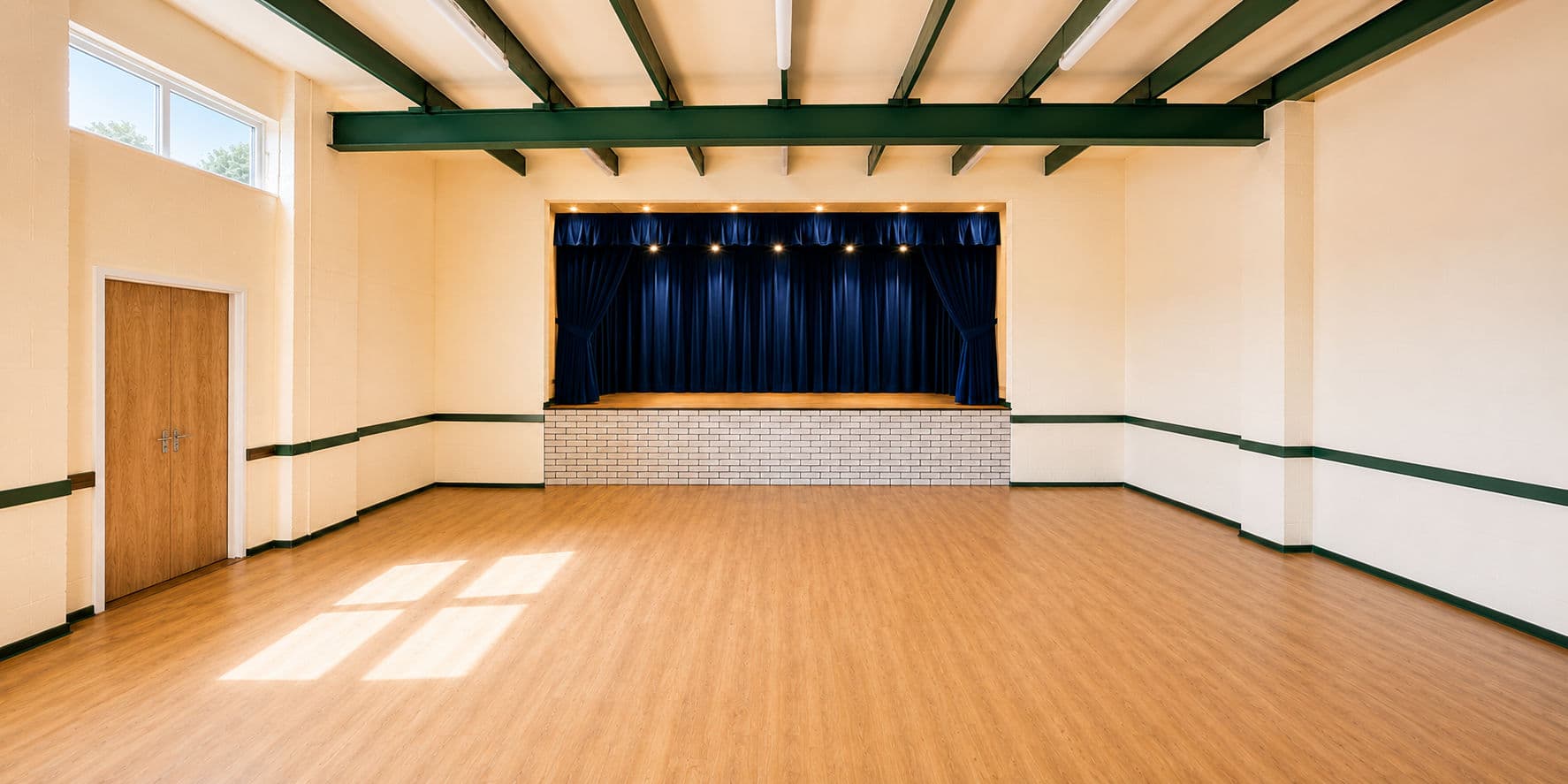 Inside the main hall at Sutton Community Hall, with a stage, curtains and wooden floor